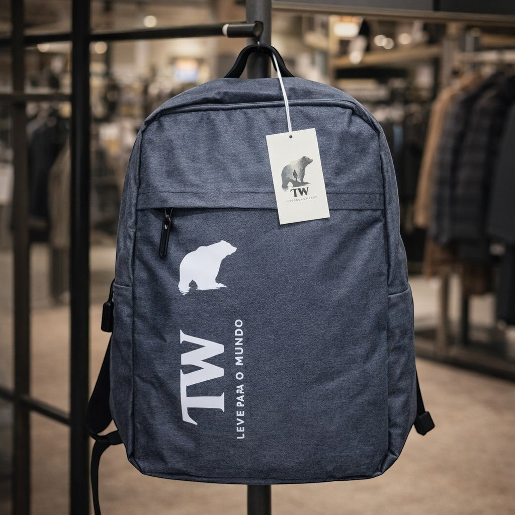 Mochila TW azul mescla com estampa de urso e logo TW Leve para o Mundo. Possui bolso frontal e entrada USB.